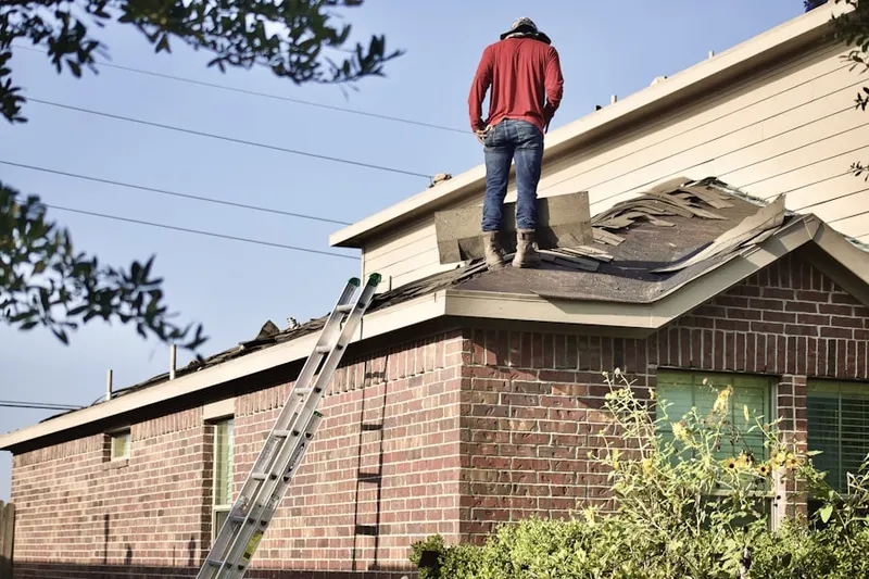 Professional roofer working on a residential roof in Warners